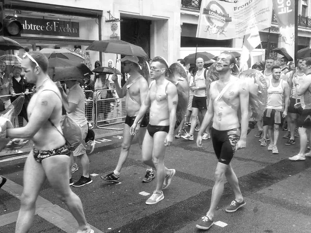 In this black and white picture there are men walking on the road. They are holding umbrellas in...